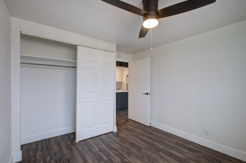 an empty living room with a ceiling fan and a closet