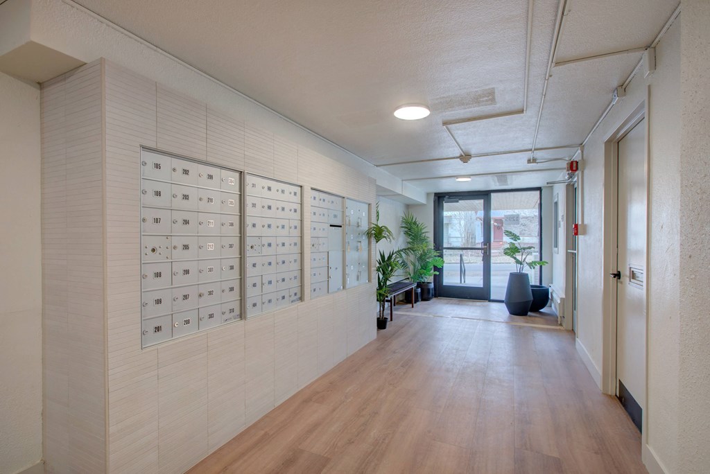 a long hallway with white walls and wooden floors and a lockers