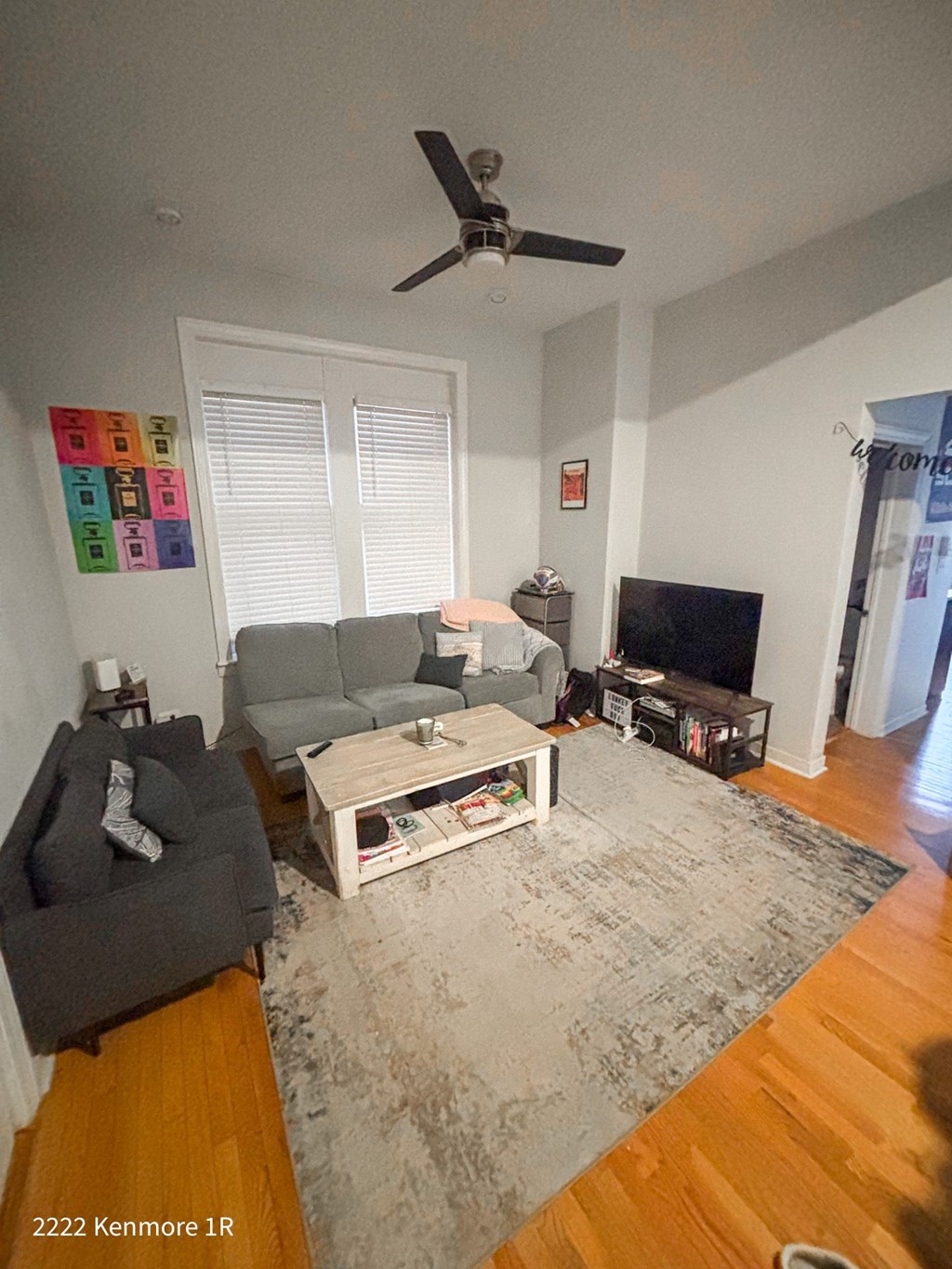 A living room with a grey couch, a white coffee table, and a ceiling fan.
