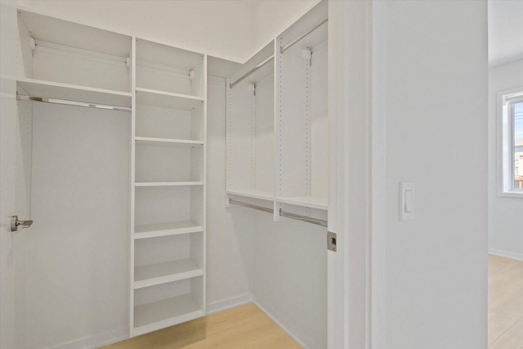 a walk in closet with white shelves and a white door