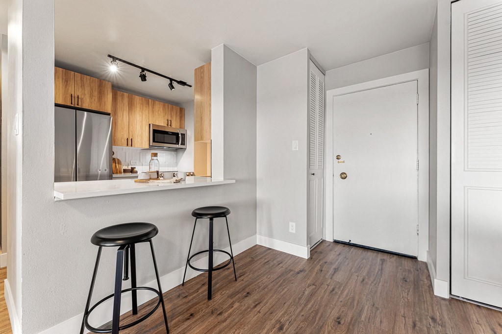 a kitchen with two stools in front of a kitchen breakfast bar