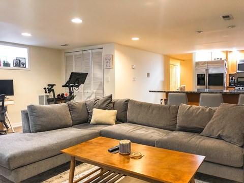 A grey couch with a wooden coffee table in front of it.