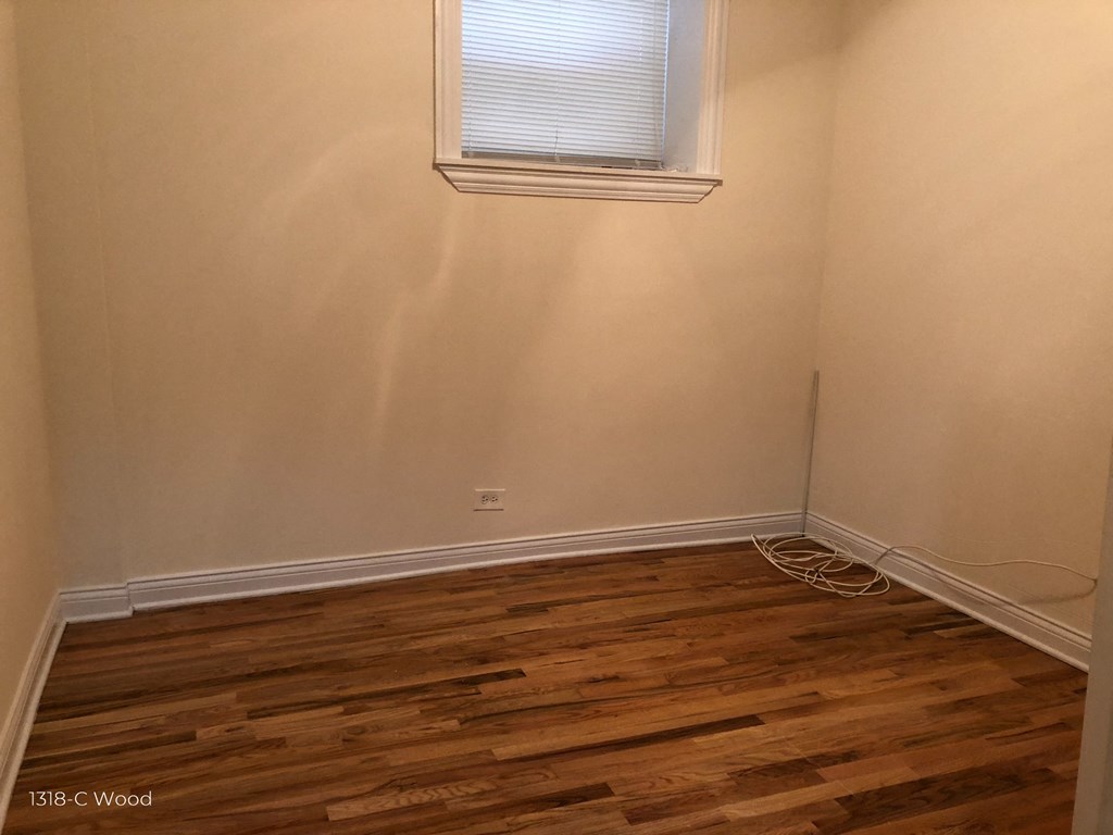 the corner of a room with wooden floors and a window