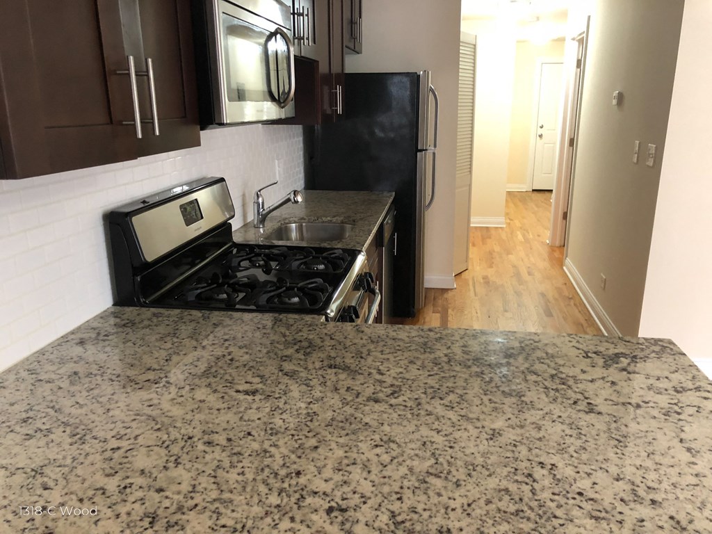 a kitchen with granite countertops and a stove and a refrigerator