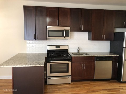 a kitchen with dark wood cabinets and stainless steel appliances and a marble counter top