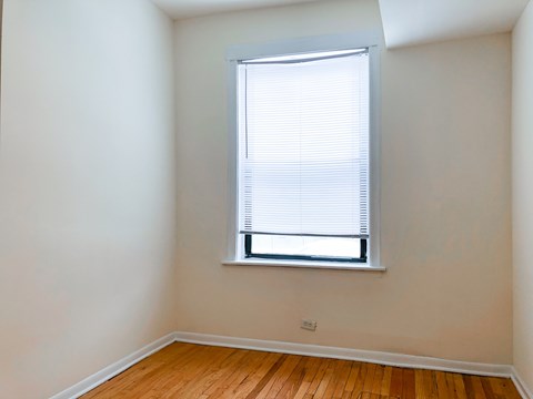 A room with a window and wooden flooring.