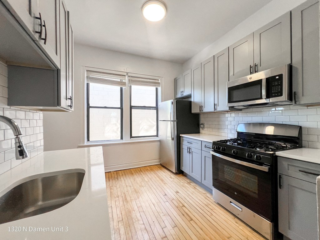 an updated kitchen with white cabinets and stainless steel appliances