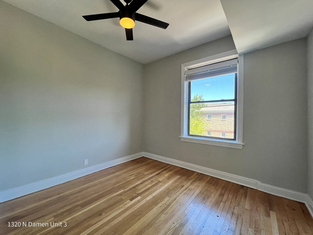 an empty room with a window and a ceiling fan