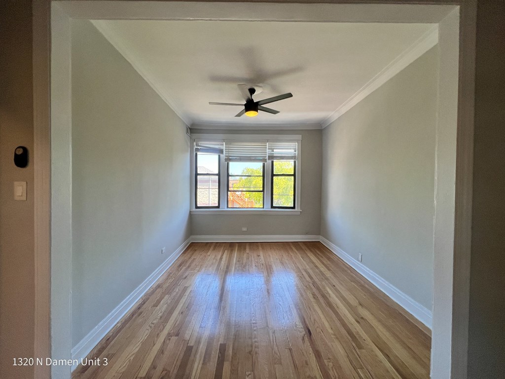 an empty room with wood floors and a ceiling fan