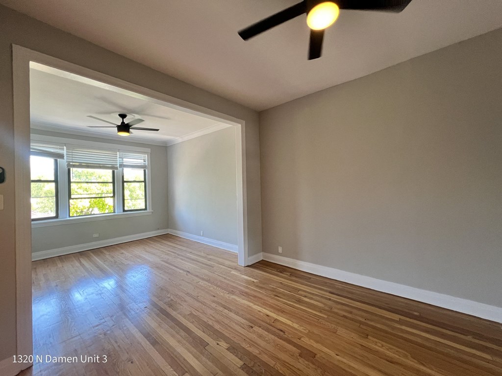an empty living room with a ceiling fan and a window