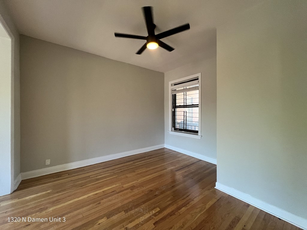 an empty living room with wood floors and a ceiling fan