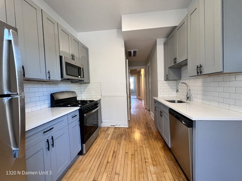 an empty kitchen with white cabinets and stainless steel appliances