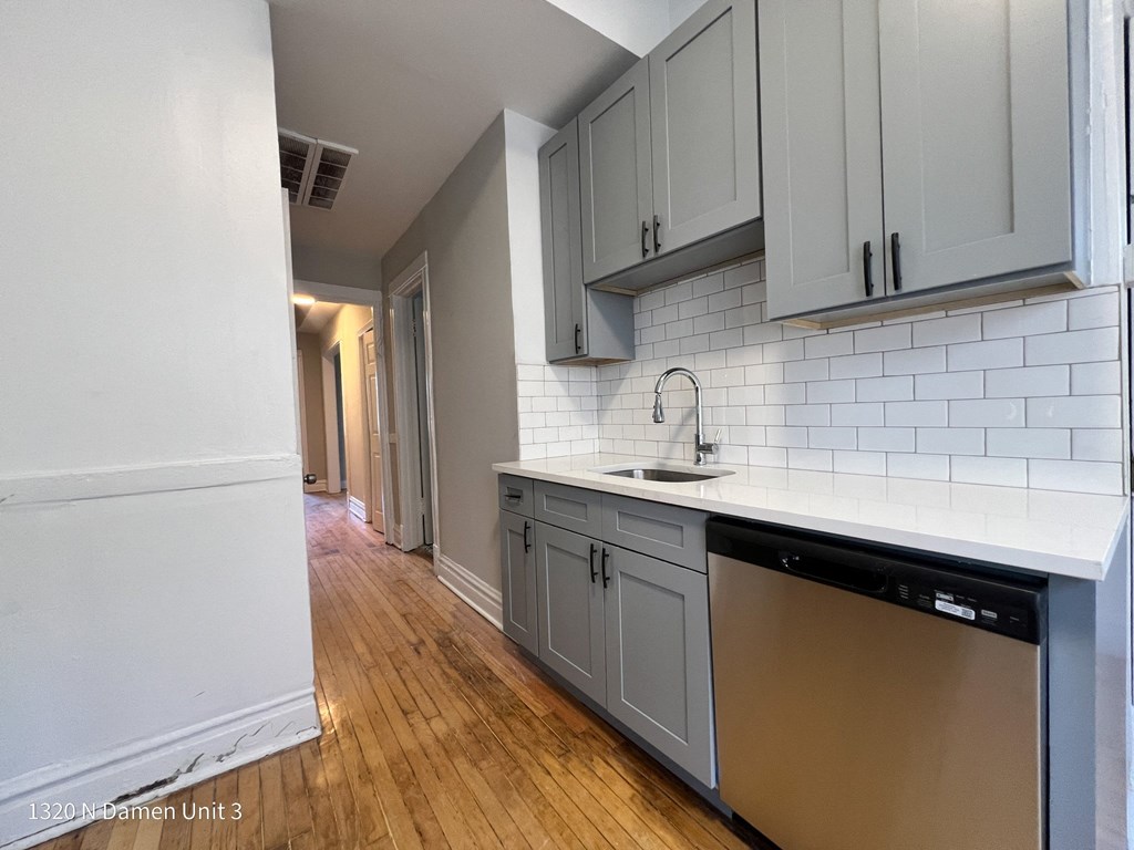an empty kitchen with white cabinets and a sink and a counter