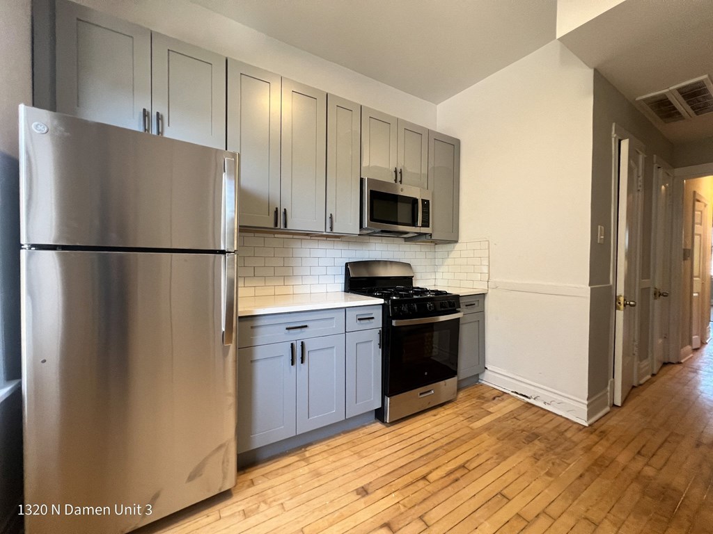 an empty kitchen with stainless steel appliances and white cabinets