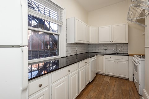 A kitchen with white cabinets and a black counter top.