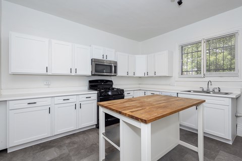A kitchen with white cabinets and a wooden island.