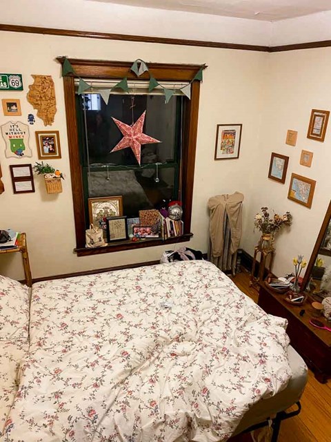 A bedroom with a floral bedspread and a mirror with a starfish decoration.