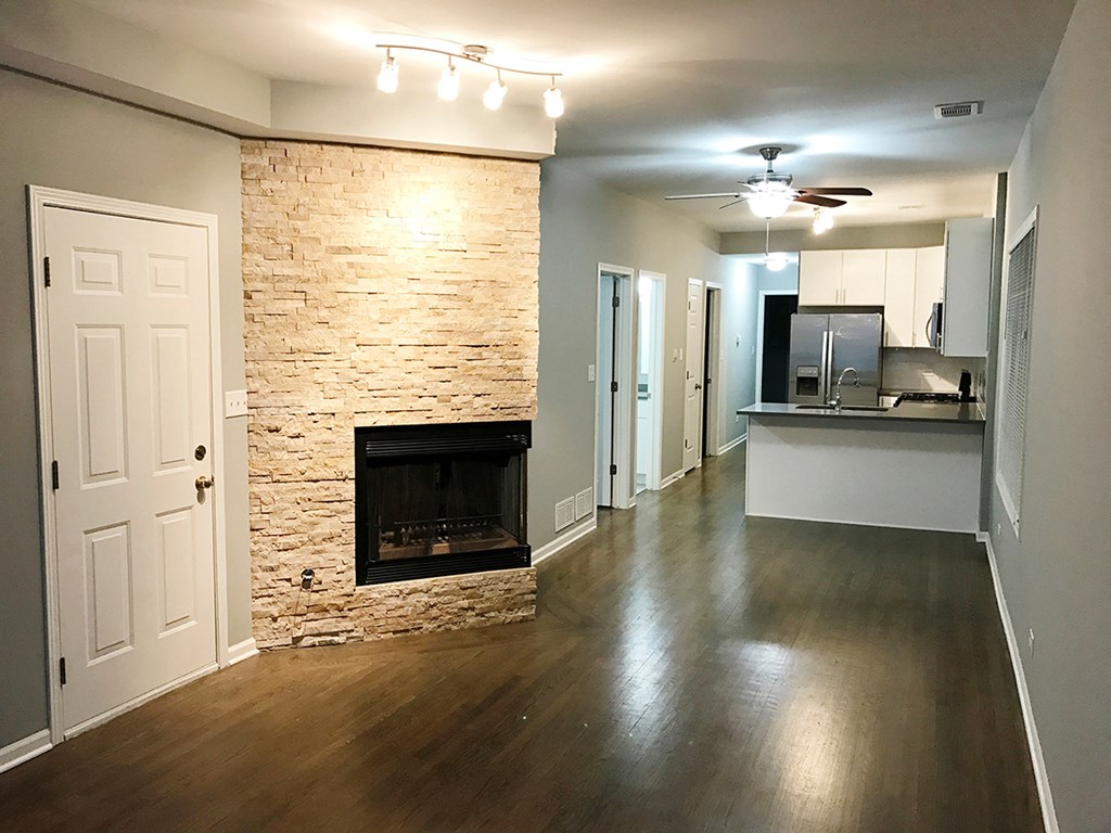 an empty living room with a stone fireplace