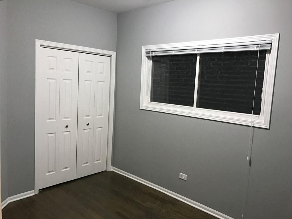 an empty room with a window and two closets