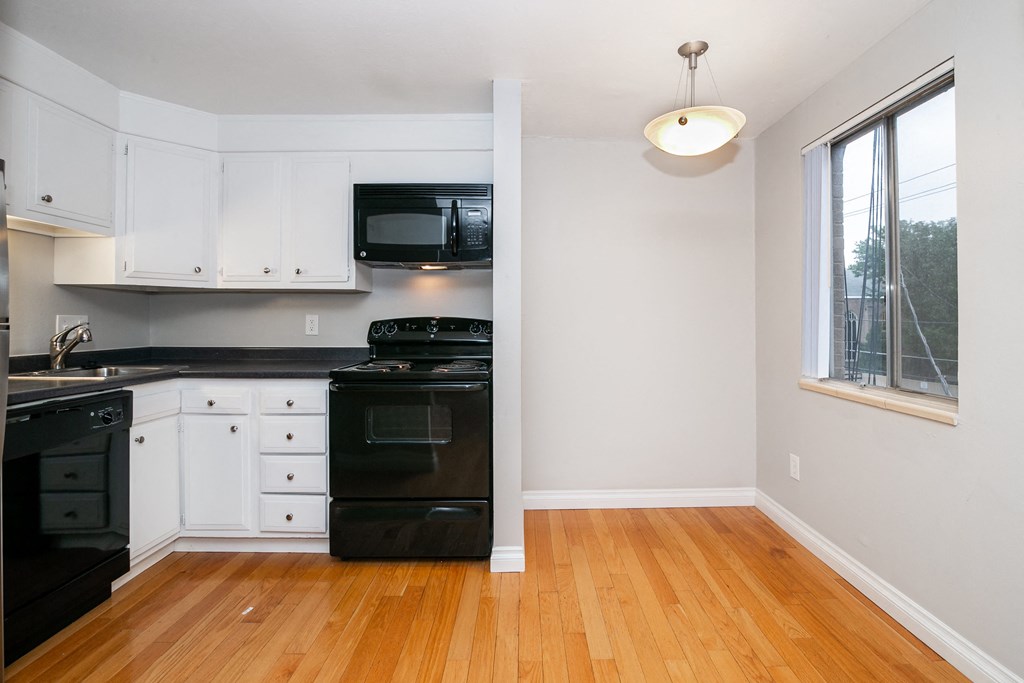 an empty kitchen with black appliances and white cabinets
