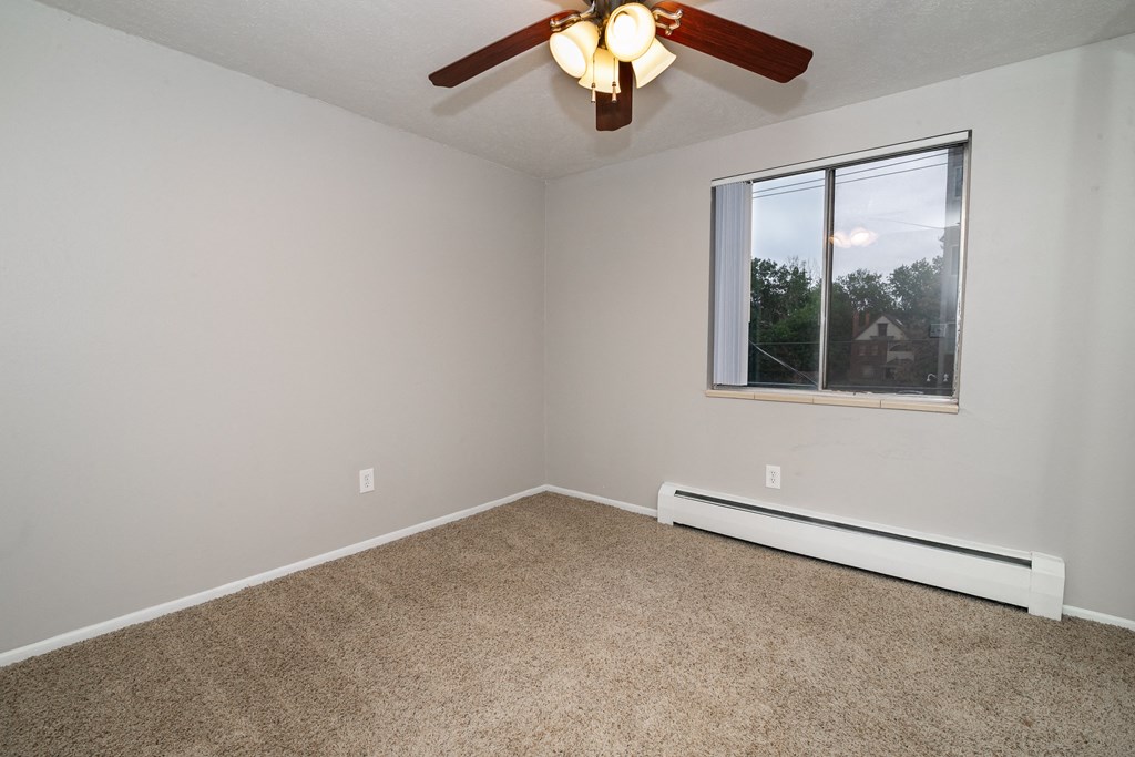 an empty room with a ceiling fan and a window