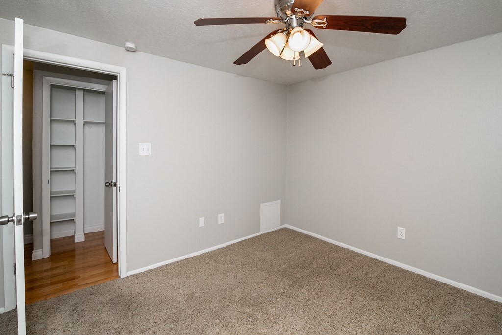 an empty room with a ceiling fan and a door to a closet