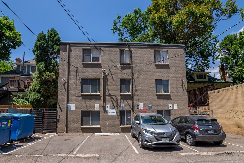 a brick apartment building with cars parked in a parking lot
