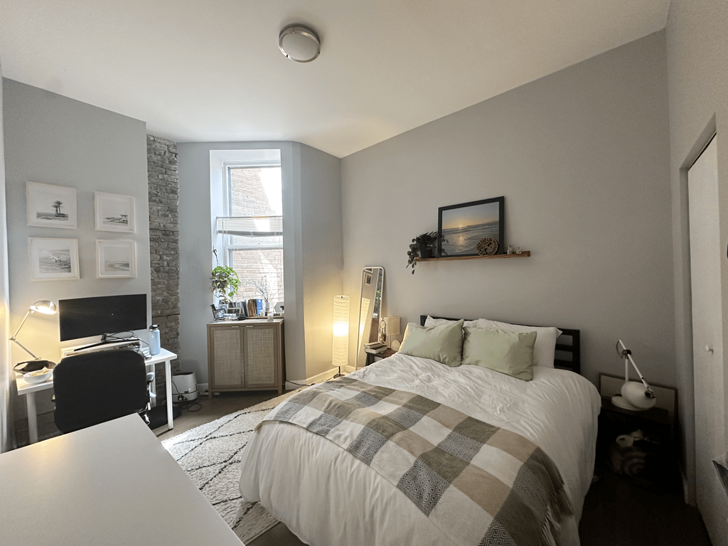 a bedroom with a bed and a desk with a computer