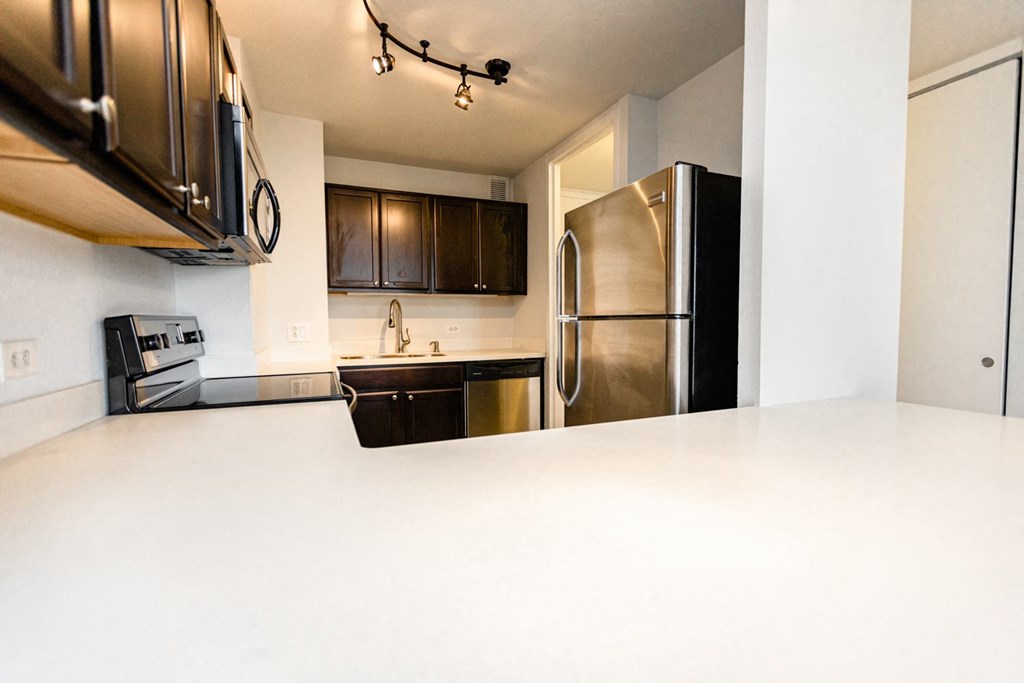 a kitchen with a white counter top and a stainless steel refrigerator