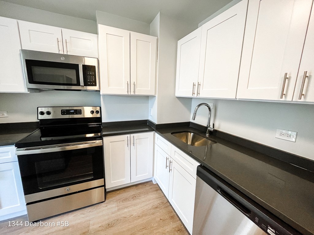 a kitchen with white cabinets and black counter tops and stainless steel appliances