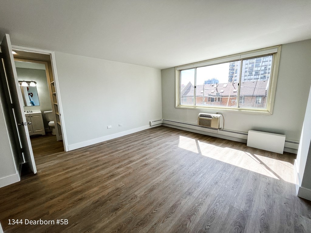 an empty living room with wood floors and a large window