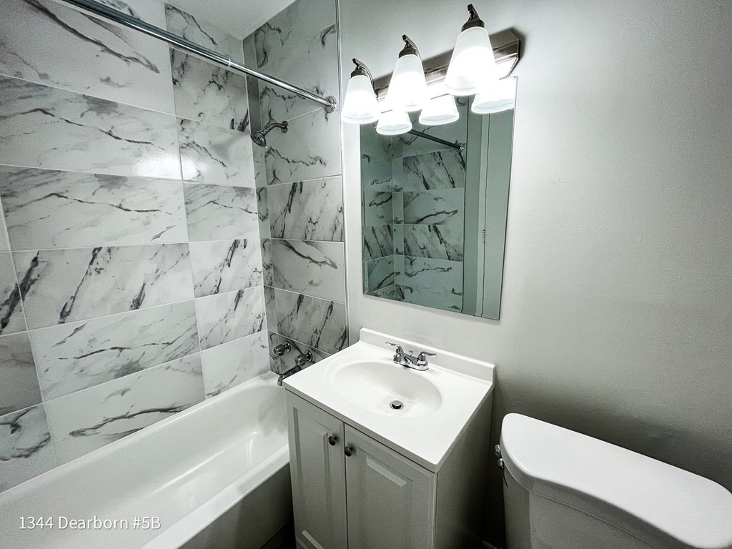 a white bathroom with a sink and a mirror and a tub