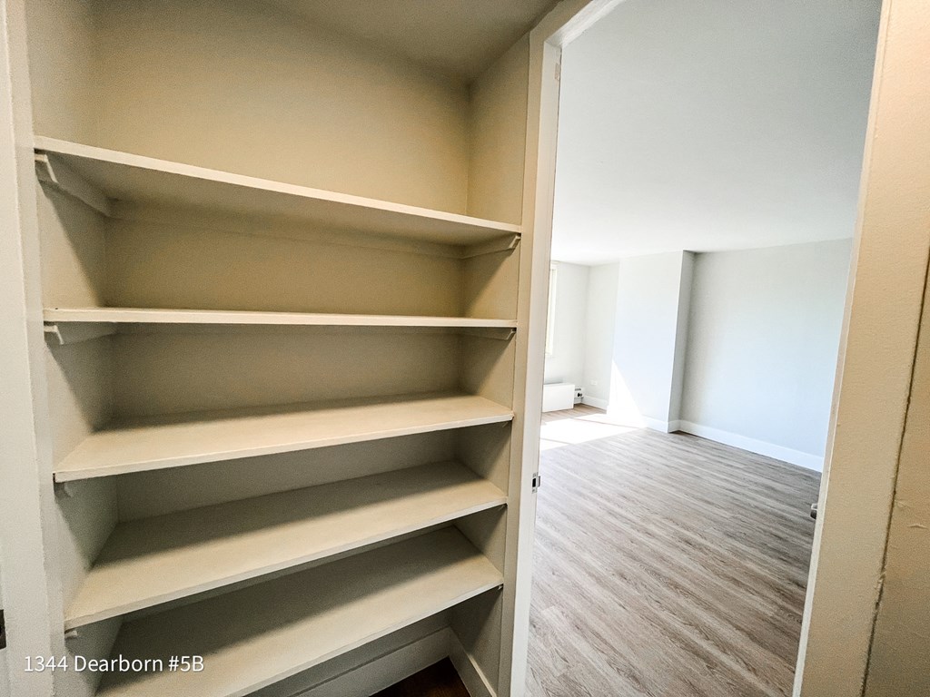 a walk in closet with empty shelves in a empty room
