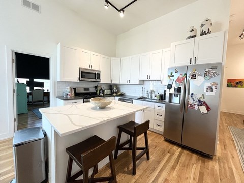 A kitchen with a white counter top and a fridge with magnets on it.