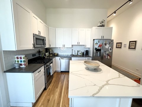 A kitchen with white cabinets and a marble counter top.