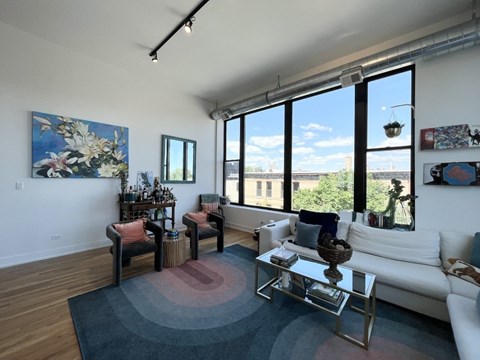 A living room with a white couch, a coffee table, and a large window.