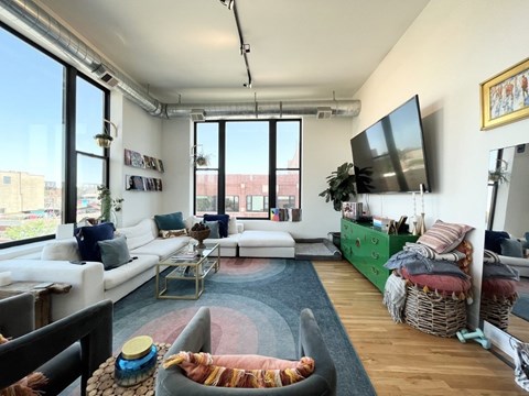 A living room with a white couch, a coffee table, and a TV on the wall.