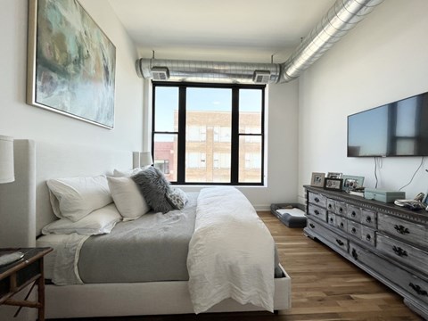 A bedroom with a large bed, a dresser, and a painting on the wall.
