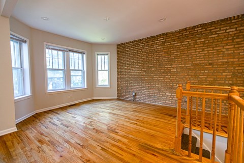 A room with wooden floors and a brick wall.