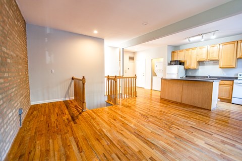 A kitchen with wooden floors and a brick wall.