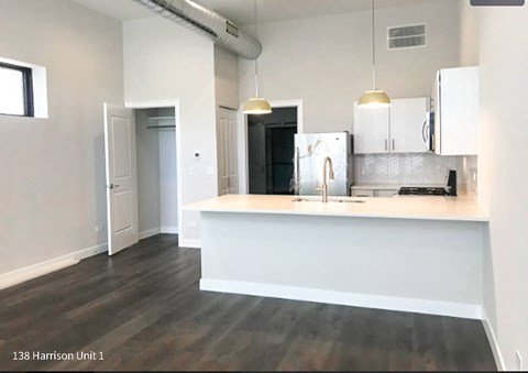 A kitchen area with a refrigerator, sink, and cabinets.