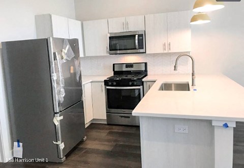 A kitchen with a white counter top and a refrigerator with a broken door.