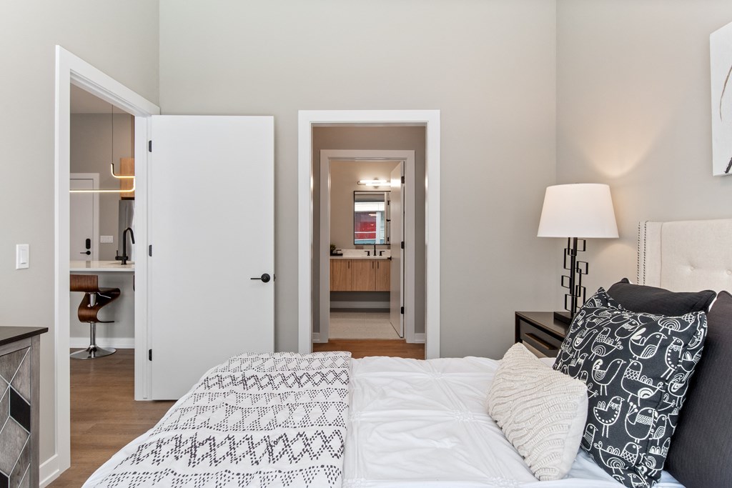 a bedroom with a bed and a view of a bathroom and a kitchen