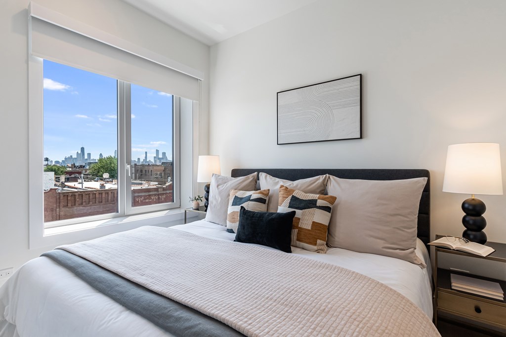 A bedroom with a large bed and a view of the city through the window.
