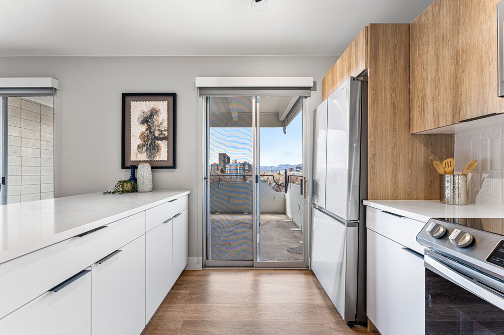 a kitchen with white cabinets and stainless steel appliances and a door to a balcony
