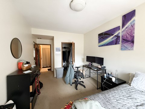 A bedroom with a bed, desk, and chair.