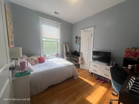 A bedroom with a bed, a chair, and a TV.