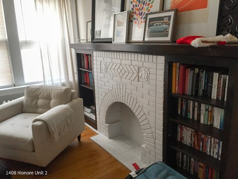 A white chair sits in front of a fireplace in a living room.