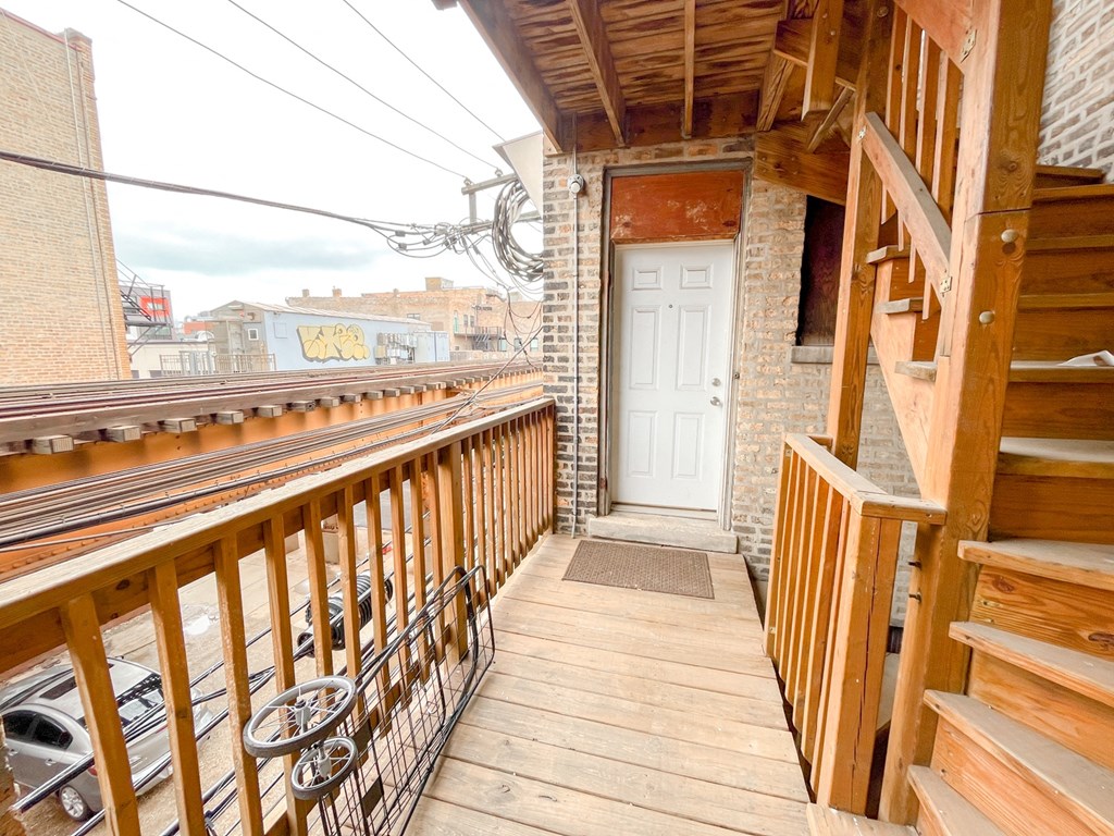 the balcony of a house with a white door and wooden stairs