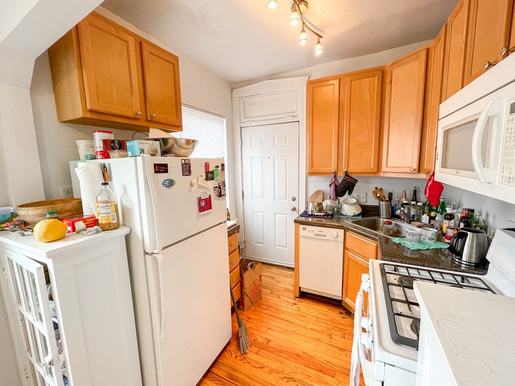 a kitchen with white appliances and wooden cabinets
